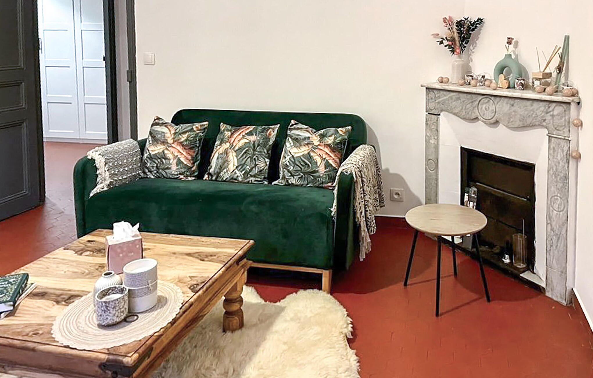 Una sala de estar con un sofá verde, una chimenea, una mesita de centro y una pequeña mesa redonda.