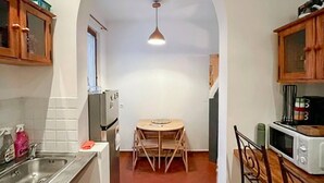 A narrow kitchen with a dining table, wooden cabinets, a refrigerator, and a microwave. - 3 bedroom pet friendly home in Vence (Vence)