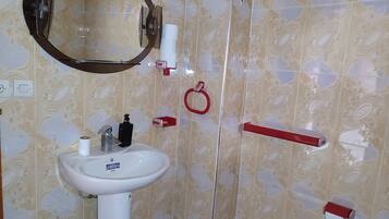 A bathroom with a sink, mirror, toilet paper holder, and a red towel rack.