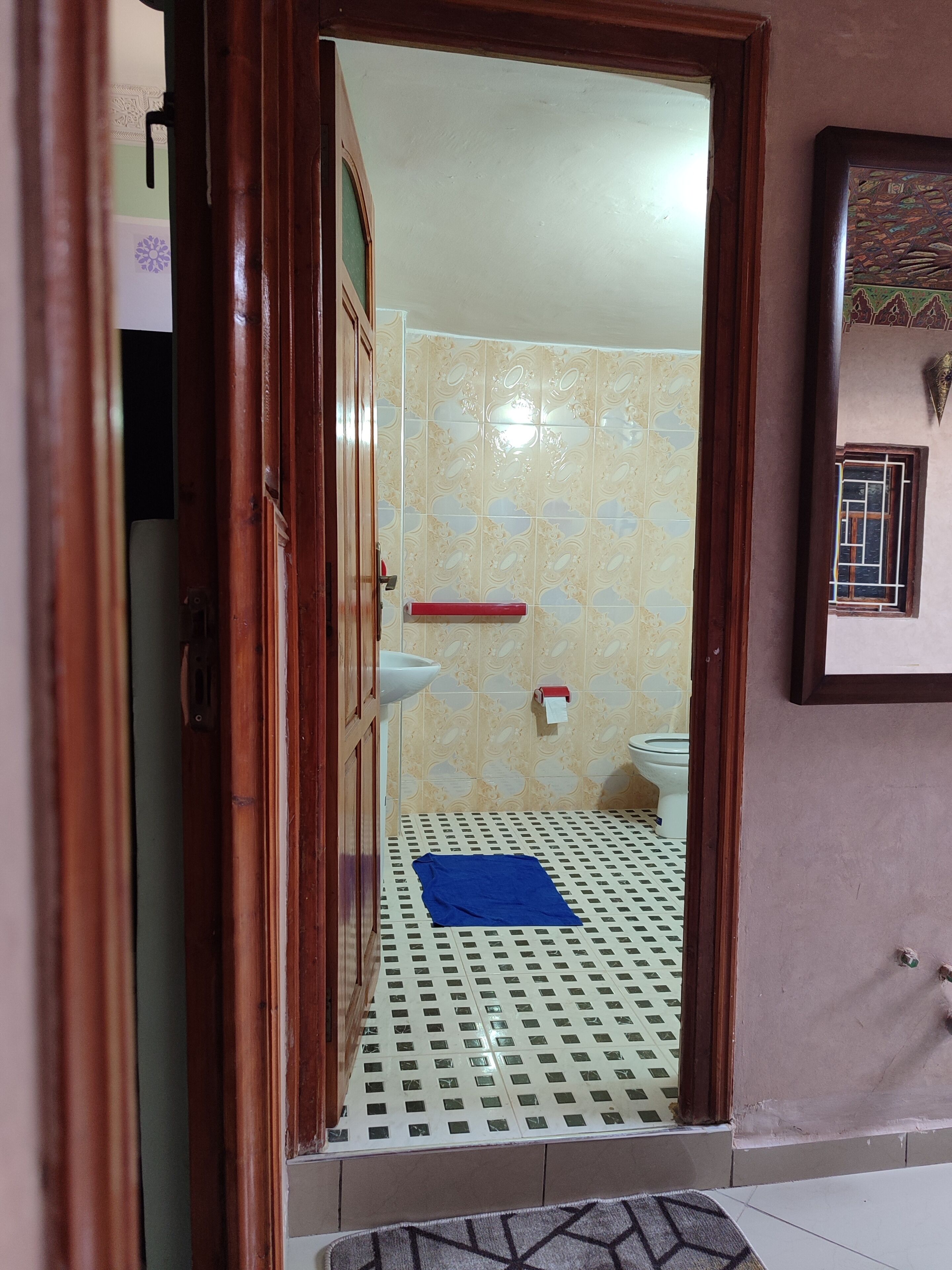 Un baño con baldosas estampadas, un inodoro, un lavabo y un felpudo azul en el suelo.