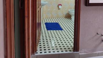 Un baño con baldosas estampadas, un inodoro, un lavabo y un felpudo azul en el suelo.