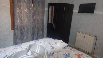 Un dormitorio con cama, armario, espejo y radiador.