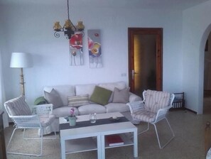 Un salon comprenant un canapé, deux fauteuils, une table basse, une lampe et des œuvres d’art murales.