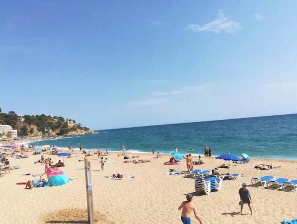 Une plage où l’on peut voir des gens se prélasser au soleil, des parasols et des chaises de plage.