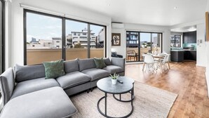 Een moderne woonkamer met een modulaire bank, een ronde salontafel en een eethoek met een tafel en stoelen.
