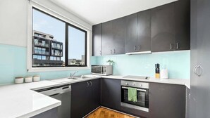 Een moderne keuken met donkere kastjes, een magnetron, een fornuis en een vaatwasser.