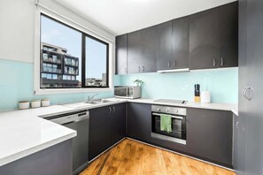 Una cocina moderna con armarios oscuros, microondas, estufa y lavavajillas.