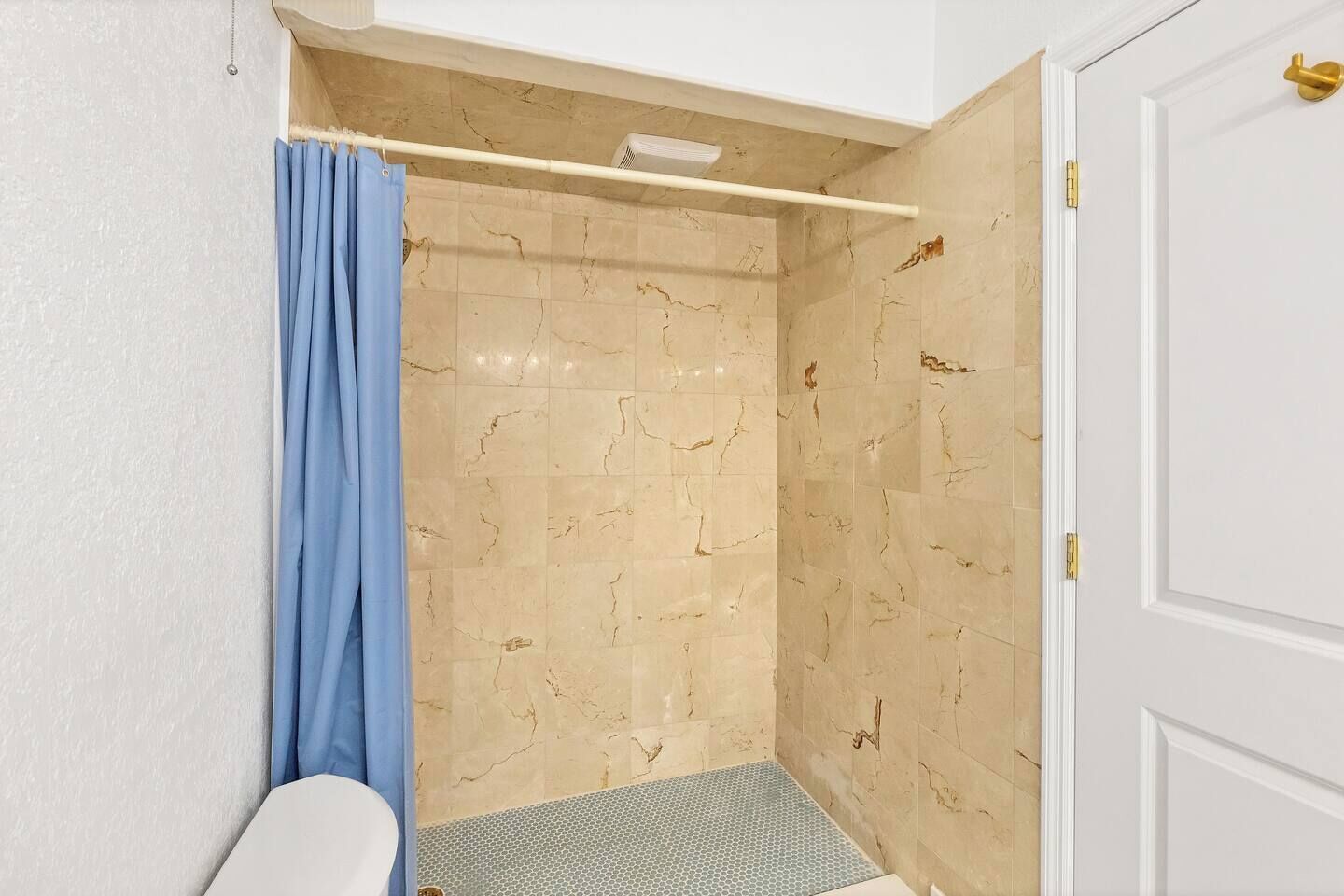 Ein Badezimmer mit Dusche, einer weißen Tür und einem Handtuchhalter.