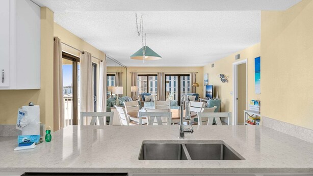 Una cucina moderna con un'isola grande, un'area pranzo con sedie e vista attraverso le porte in vetro.