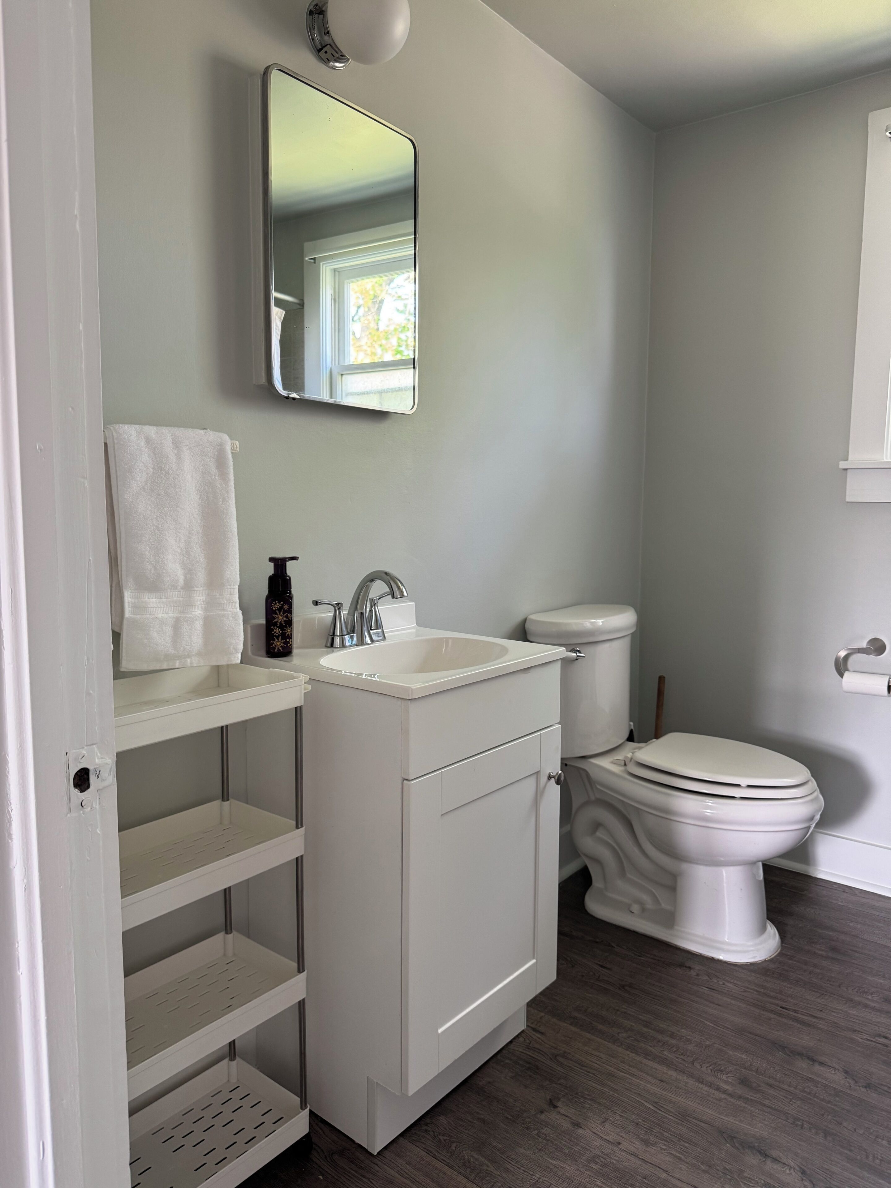 Un baño con lavamanos blanco, inodoro y estantes.