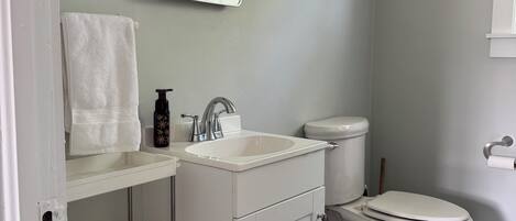 Un baño con lavamanos blanco, inodoro y estantes.