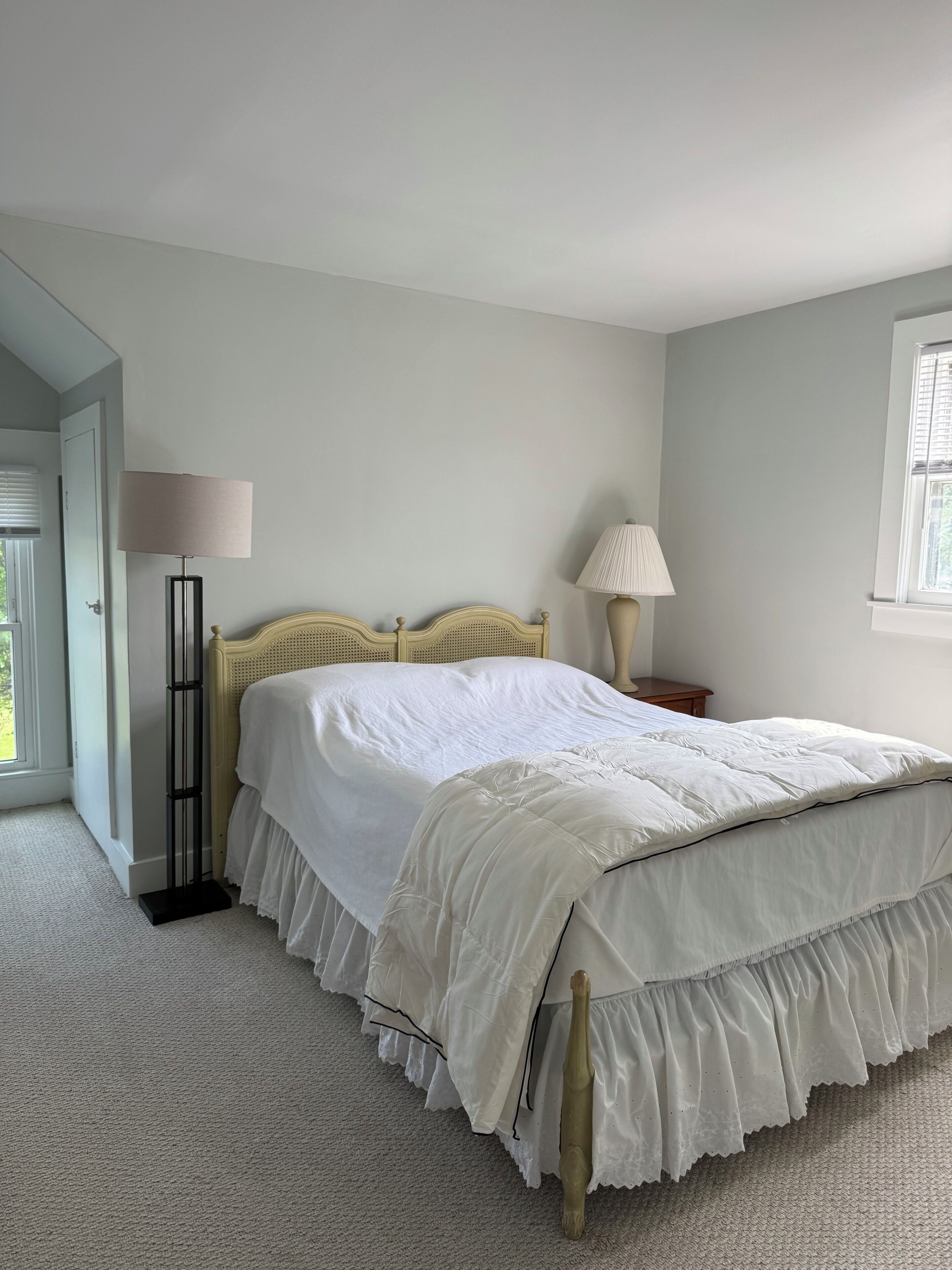 A bedroom with a bed, two bedside lamps, a window, and a door.
