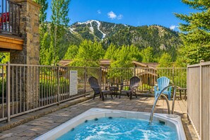 A hot tub with a mountain view, outdoor seating, and a spa rules sign. - Luxury Timbers Townhome | Walk to Town & Ski (Ketchum)