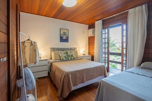 Un dormitorio con cama, mesita de noche, lámpara y ventana con cortinas.