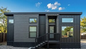 En moderne bygning i to etager med mørk facade, en central trappe og mange vinduer.