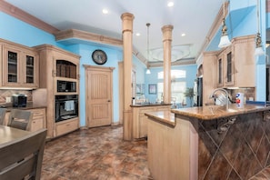 A kitchen with wooden cabinets, a central island, and a clock on the wall. - Villa MeMe with private pool  - 89BP (Laguna Vista)