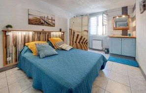 Ein Schlafzimmer mit Bett, Nachttisch, Spiegel, Heizkörper und Fenster.