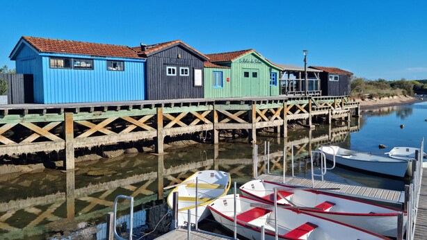 A row of colorful wooden buildings on stilts by a calm water body, with boats docked in the foreground. - 1 bedroom beautiful home in Rivedoux-Plage (Rivedoux-Plage)