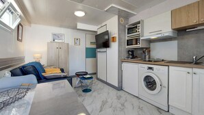 A compact hotel room with a bed, bedside table, lamp, and a small kitchenette with a microwave, oven, and washing machine. - 1 bedroom beautiful home in Rivedoux-Plage (Rivedoux-Plage)