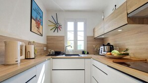 A modern kitchen with a central island, a window, and a clock on the wall.