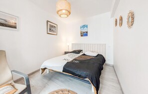 Ein Schlafzimmer mit Bett, Sessel, Pendelleuchte und Wanddekorationen.