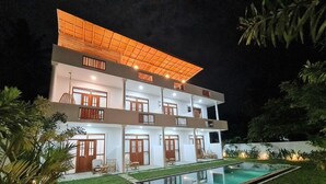 A two-story building with a swimming pool, multiple balconies, and a well-lit exterior. - Ohana Surf Guest House (Ahangama)