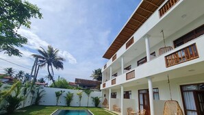 A two-story building with a swimming pool, outdoor seating, and a white exterior. - Ohana Surf Guest House (Ahangama)