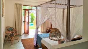 A room with a bed, a chair, a fan, and a view of the outdoors. - Ohana Surf Guest House (Ahangama)