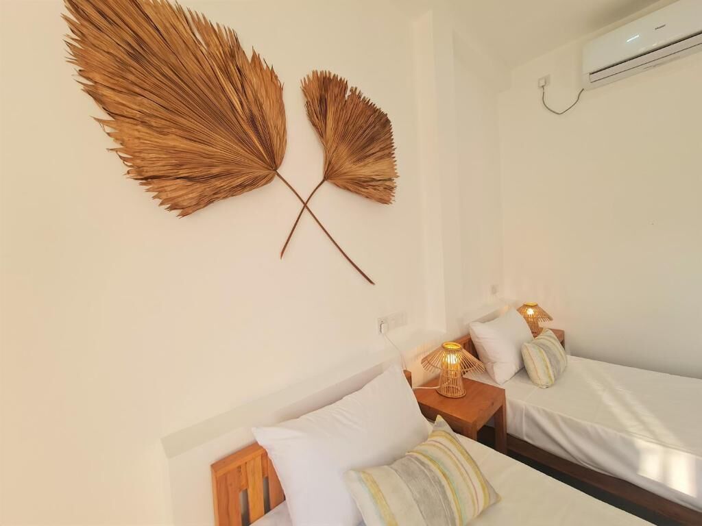 A room with two beds, a wall-mounted air conditioner, and a decorative wall piece.
