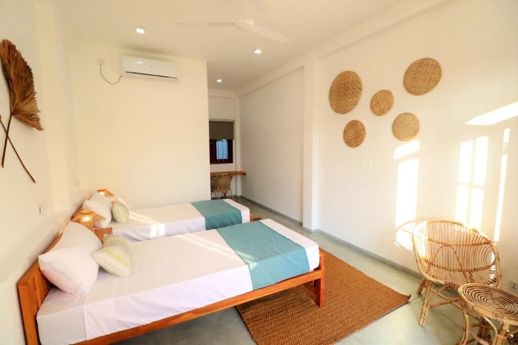 A room with two beds, a chair, a TV, and a wall-mounted air conditioner.