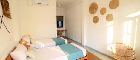 A room with two beds, a chair, a TV, and a wall-mounted air conditioner.