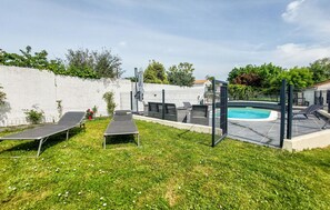 Ein Garten mit Swimmingpool, Liegestühlen und einem eingezäunten Bereich.
