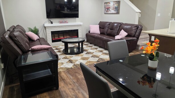 Una sala de estar moderna con un televisor de pantalla plana, sofás de cuero, una mesa de centro de vidrio y una chimenea.