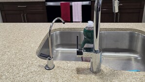Una cocina con un lavamanos de acero inoxidable, un microondas y una estufa.