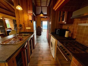 A wooden interior with a kitchen, a washing machine, and a view to the outside.