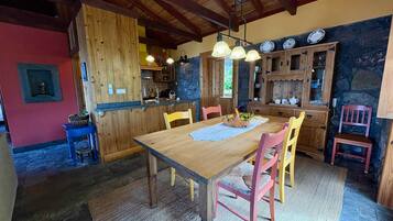 A rustic kitchen with wooden cabinets, a dining table with chairs, and a stone wall.