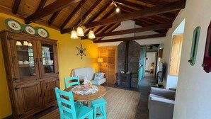 Una cocina rústica con armarios de madera, una mesa de comedor con sillas turquesas y una chimenea de piedra.