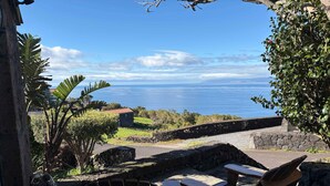 Un patio con sillas y una mesa de madera con vista al mar.
