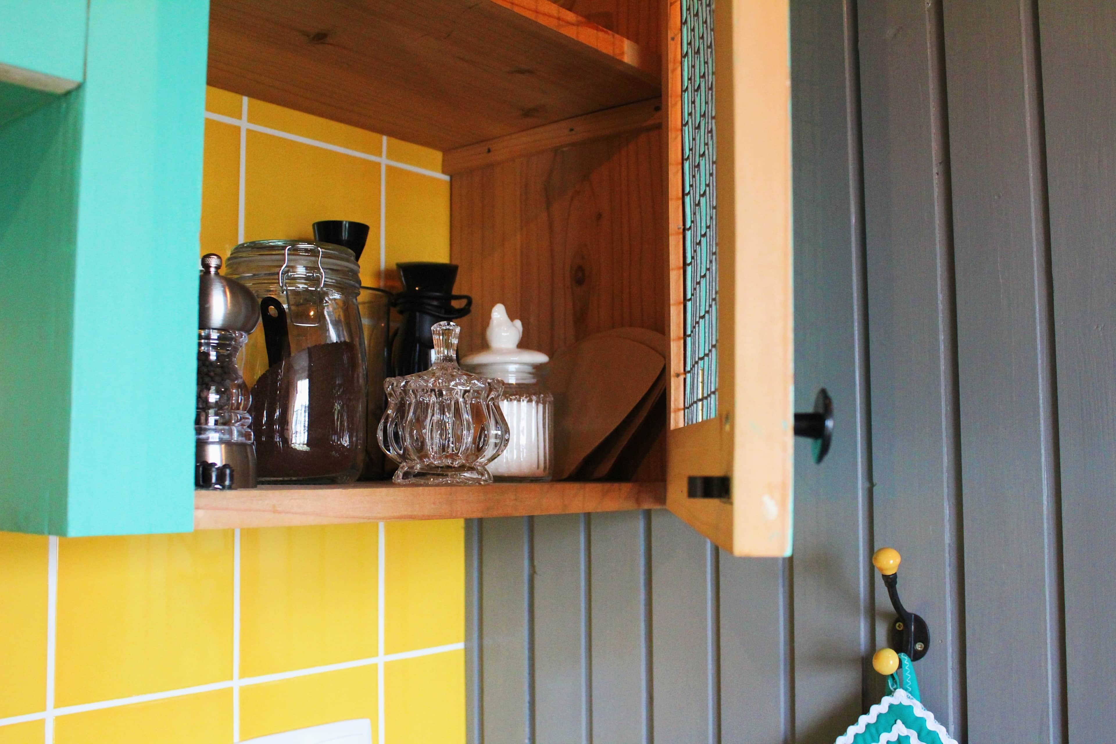 Een keuken met een houten plank waarop verschillende keukengerei staat en een deur met een metalen handgreep.