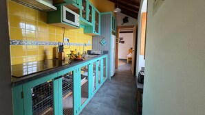 Una cocina con armarios azul verdoso, baldosas amarillas y techo de madera.