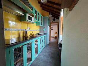 Une cuisine avec des armoires de couleur turquoise, des carreaux jaunes et un plafond en bois.