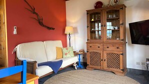 A living room with a white sofa, a wooden cabinet, a lamp, and a television. - Casa do Jardim (Santo Amaro)