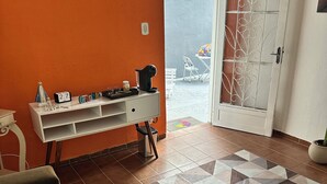 Un salon comprenant un canapé, une console blanche agrémentée d’objets décoratifs, un tapis à motifs et une porte donnant sur l’extérieur.