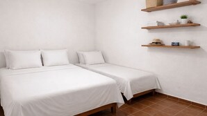 Une chambre avec deux lits, un ventilateur de plafond et des étagères en bois où sont posés divers objets.
