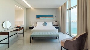A modern hotel room with a large bed, bedside tables, a desk, a chair, and a view of the sea. - Th8 Palm Dubai Beach Resort, Vignette Collection (Dubai)