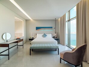A modern hotel room with a large bed, bedside tables, a desk, a chair, and a view of the sea. - Th8 Palm Dubai Beach Resort, Vignette Collection (Dubai)