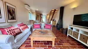 A living room with a sofa, coffee table, TV stand, fireplace, and staircase.
