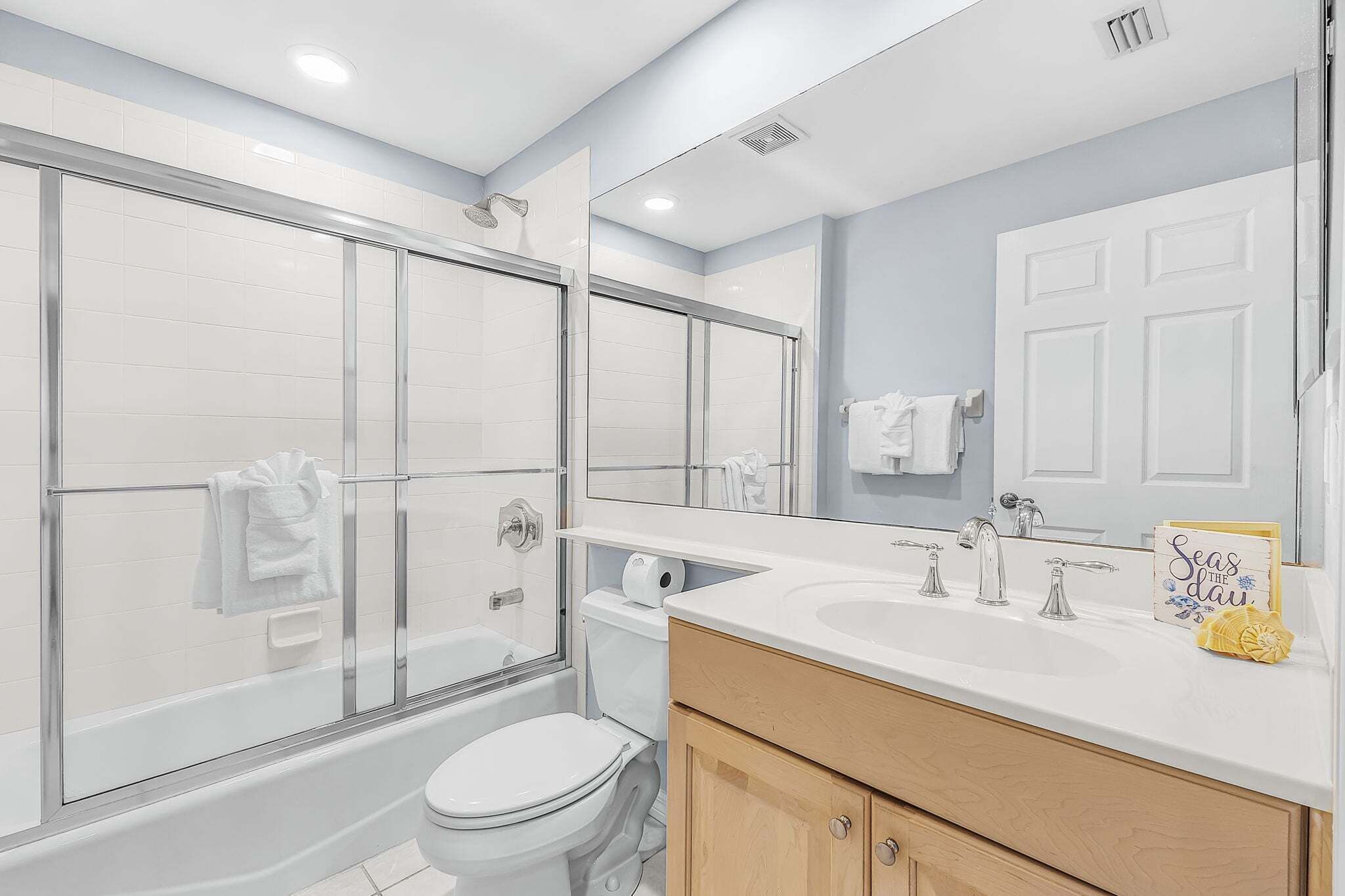 A modern bathroom with a glass shower enclosure, a white toilet, a sink with a mirror, and a vanity with cabinets.