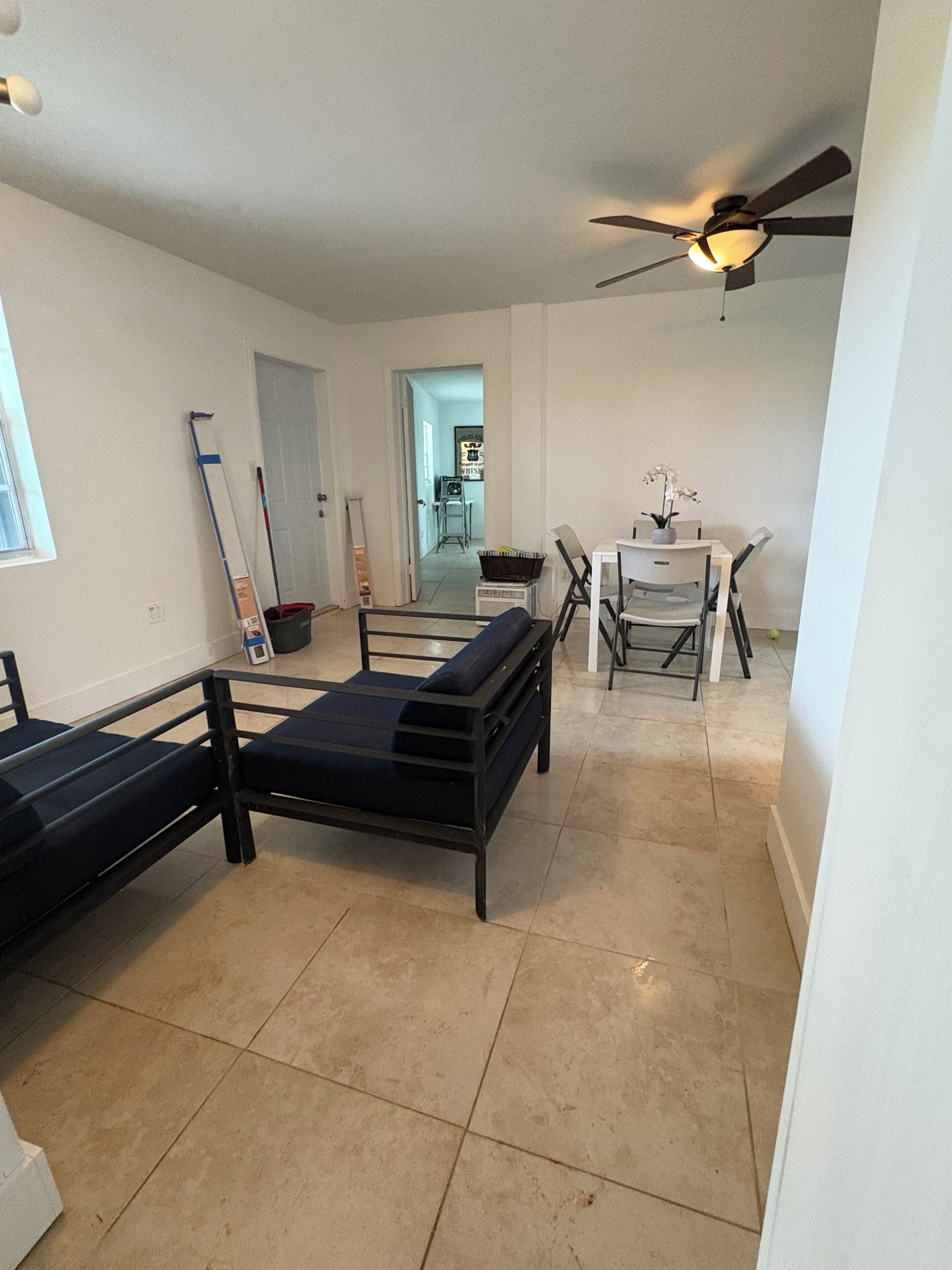 A room with a bed, a desk, a chair, and a ceiling fan.