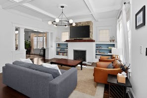 Ein Wohnzimmer mit einer Couch, einem Couchtisch, einem Kamin, einem Fernseher und Bücherregalen.